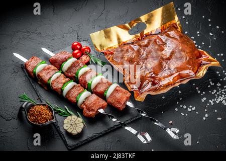 Viande grillée emballée sous vide, sur fond sombre. Shashlyk frais Banque D'Images