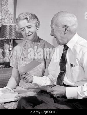 1950s couple senior assis sur un canapé femme a un magazine dans son homme souriant de genoux montrant son chèque qu'il vient de recevoir PAR LA POSTE - S8291 HAR001 HARS SATISFACTION FEMMES AÎNÉES MARIÉES MONTRANT LE CONJOINT MARI MAISON VIE COPIE ESPACE AMITIÉ DEMI-LONGUEUR DAMES PERSONNES HOMMES JUSTE RETRAITE SENIOR HOMME B&W PARTENAIRE LAP SENIOR FEMME RETRAITÉ BONHEUR VIEILLESSE OLDSTERS GAI OLDSTER EN ONTARIO LES AÎNÉS SOURIT LA PENSION JOYEUX HOMME ÂGÉ A REÇU LA SÉCURITÉ SOCIALE DES FEMMES DE TOGETHNESS NOIR ET BLANC DE RACE BLANCHE HAR001 ANS À LA MODE Banque D'Images