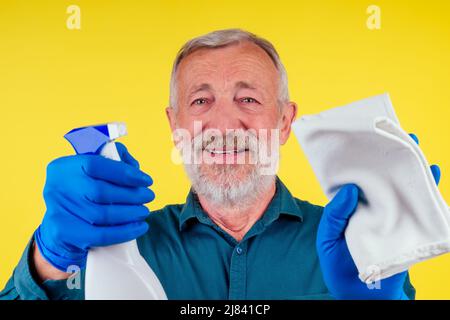 Portrait d'un homme avec une serviette et un spray prêt à nettoyer les fenêtres sur fond jaune studio Banque D'Images