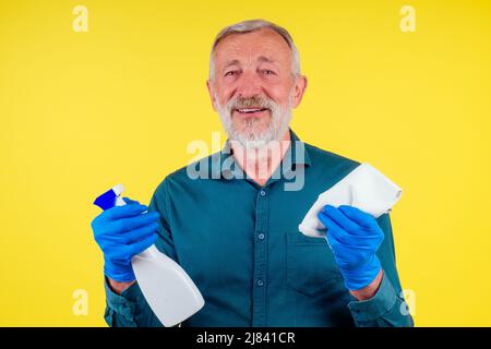 Portrait d'un homme avec une serviette et un spray prêt à nettoyer les fenêtres sur fond jaune studio Banque D'Images