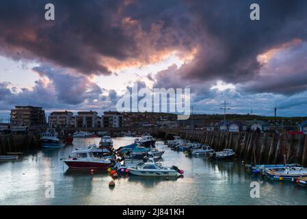 West Bay, Dorset, Royaume-Uni. 12th mai 2022. Météo Royaume-Uni. Nuages sombres menaçant au-dessus du port pendant le coucher du soleil à la station balnéaire de West Bay à Dorset. Crédit photo : Graham Hunt/Alamy Live News Banque D'Images