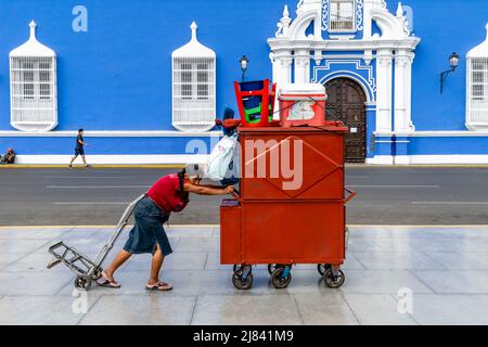 Une femme âgée pousse son kiosque alimentaire mobile à travers la Plaza de Armas, Trujillo, région de la Libertad, Pérou. Banque D'Images