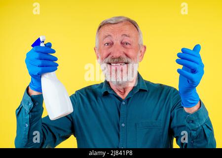 Portrait d'un homme avec une serviette et un spray prêt à nettoyer les fenêtres sur fond jaune studio Banque D'Images