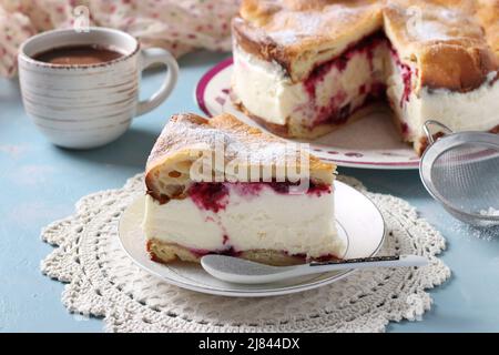 Karpatka aux cerises, tarte traditionnelle à la crème polonaise sur fond bleu clair. Format horizontal Banque D'Images