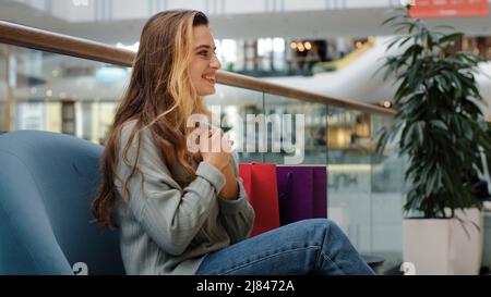 Réussi bonne jeune fille shopaholic femme client acheteur assis dans le centre commercial avec des sacs à la recherche de téléphone gagnant la victoire offre d'escompte se réjouir Banque D'Images