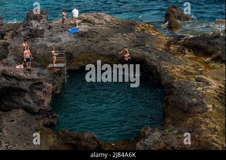 Ténérife, Espagne. 12th mai 2022. Une femme saute dans l'eau tandis que les touristes et les habitants de la région aiment bronzer dans une piscine d'eau salée naturelle, formée dans une zone de falaises volcaniques près de la ville de Los Abrigos. Des températures élevées sont enregistrées au cours de la semaine dans les îles Canaries. Credit: Marcos del Mazo/Alay Live News Banque D'Images