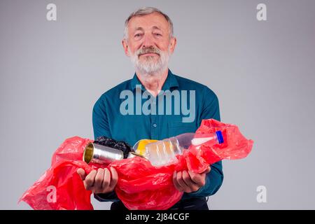 un vieil homme caucasien tient des déchets en plastique sur fond blanc de studio Banque D'Images