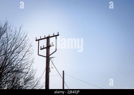 Photo d'un ancien poteau en bois, avec des câbles d'électricité autour, pris au cours d'un après-midi ensoleillé avec ses anciens et anciens câbles d'alimentation. Banque D'Images