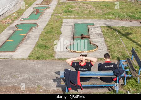 Photo d'un centre de villégiature abandonné pour minigolf avec des installations abandonnées devant deux jeunes hommes qui pleuvaient des t-shirts avec Novi Beograd écrit dessus. Nouveau B Banque D'Images