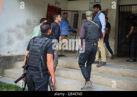 Des policiers indiens et des troopeurs paramilitaires sont mis en garde devant un bureau du gouvernement dans la région de Chadoora, dans le district de Budgam, au centre du Cachemire, où un employé de la communauté de Kashmiri Pandit a été abattu par des militants. Cette attaque survient un jour après deux rencontres séparées dans les districts de Bandipora et d'Anantnag dans la région contestée. Banque D'Images