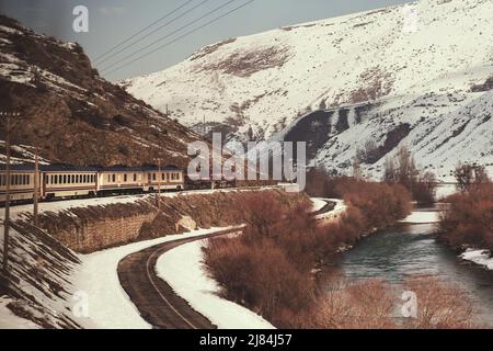 Erzincan, Turquie - 22 février 2022 : train express de l'est, rivière et collines enneigées en hiver. Banque D'Images