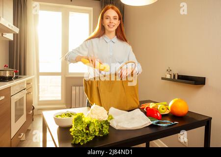 écologique redhaired ginger femme trier les achats de coton eco sac cuisine coucher de soleil lumière background.no plastique paquet vert paix Banque D'Images