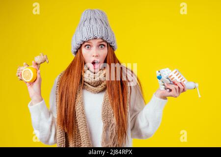 maladie femme redhaired portant pull tricoté, chapeau avec foulard choix entre citron naturel et gingembre remède populaire pour le rhume et tas de pilules Banque D'Images