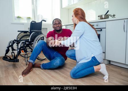 Jeune homme afro-américain handicapé barbu en fauteuil roulant et sa jolie femme au kichen Banque D'Images