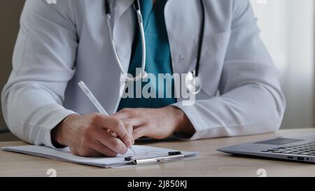 Homme thérapeute qualifié avec stéthoscope remplissant la forme médicale remarquant réception concluant jeune praticien prescrivant un traitement pour le patient mâle Banque D'Images