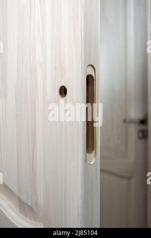 Installation d'une serrure sur une porte en bois. Trou fraisé et percé dans une porte en bois, préparé pour l'installation d'une serrure. Banque D'Images