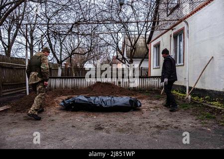 Lipovka, Ukraine. 10th avril 2022. Un soldat de la défense territoriale et un bénévole viennent recueillir le corps d'un homme. Selon sa famille, l'homme a été empoisonné par des soldats russes.Lipovka est une petite ville de la région de Bucha située à 60 km à l'ouest de la capitale. Une zone complète de petits villages qui n'ont pas de lumière, d'eau, de gaz, de chaleur et de communication depuis plus d'un mois. Lipovka a été détruite par environ 40%, des meurtres de masse de civils par les occupants russes ont été enregistrés, des infrastructures ont été détruites, des territoires ont été extraits. Crédit : SOPA Images Limited/Alamy Live News Banque D'Images