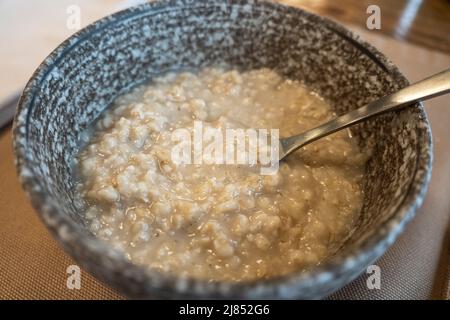 Porridge de flocons d'avoine dans une assiette avec une cuillère en gros plan. Bouillie délicieuse bouillie Banque D'Images