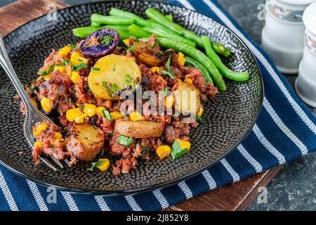 Bœuf corné, maïs sucré et hash de pomme de terre avec haricots verts Banque D'Images