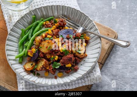 Bœuf corné, maïs sucré et hash de pomme de terre avec haricots verts Banque D'Images