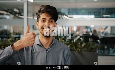 Heureux hispanique employé arabe homme leader gagnant approuver regarder la caméra montrant l'accord de pouce vers le haut signer tout beau succès gestuelle langage corporel Banque D'Images
