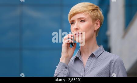 Portrait d'adulte 40s femme d'affaires mature femme patron blond avec cheveux courts visage de femme parlant sur le téléphone mobile répond à l'appel parlant en utilisant Banque D'Images