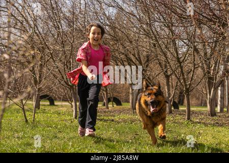petite fille qui court avec son berger allemand Banque D'Images