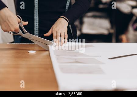 Le tailleur découpe le tissu selon le motif. Profession de tailleur et de coupeur, petite entreprise Banque D'Images