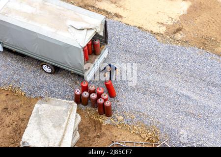 Un homme charge des bouteilles de gaz rouge dans le corps d'un camion sous un ébarbage, foyer sélectif Banque D'Images