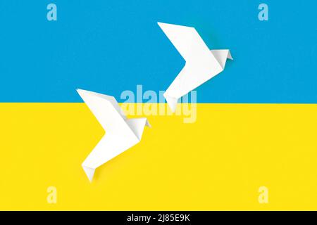 Deux feuilles de papier blanc origami sont gravées sur les couleurs du drapeau de l'Ukraine. Le concept de paix entre deux États. Symbole de paix sur fond bleu et jaune. Banque D'Images