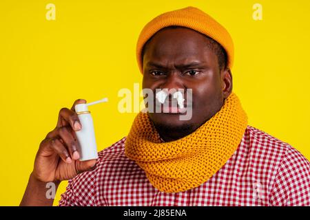 jeune afro-américain portant une chemise à carreaux rouges avec écharpe tricotée et chapeau mal avec fièvre et chaleur et frissons dans le fond jaune studio Banque D'Images