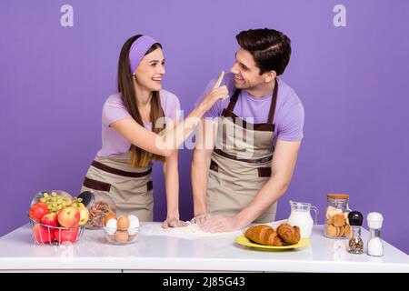 Photo de la jolie dame gars préparer la pâte doigt toucher nez isolé sur fond violet couleur Banque D'Images