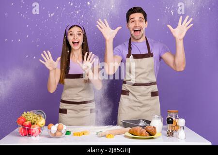 Portrait de deux partenaires fous excités lever les mains jeter le blé isolé sur fond violet de couleur Banque D'Images