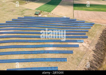 Ferme solaire vue aérienne, rangées de panneaux PV par une petite maison Banque D'Images