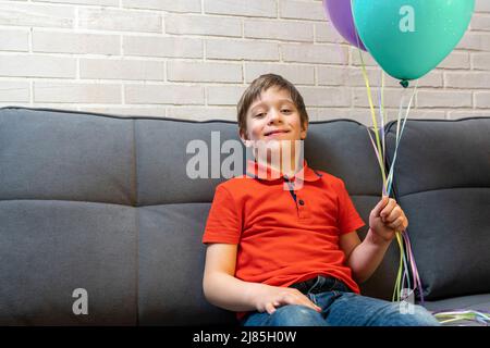 un garçon d'âge préscolaire heureux tient des ballons dans ses mains Banque D'Images