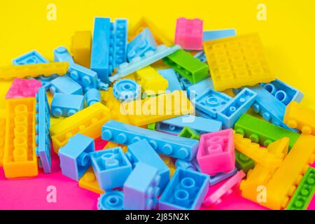 Jeu de blocs colorés, fond coloré, concept de jeu et d'apprentissage, jouets déversés pour enfants, blocs de construction, toile de fond jaune et rose, vue du dessus Banque D'Images