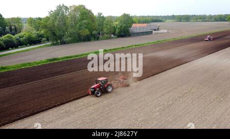 Un agriculteur laboure ses terres agricoles sèches, tandis qu'une autre machine à droite est occupée à semer des pommes de terre. Banque D'Images