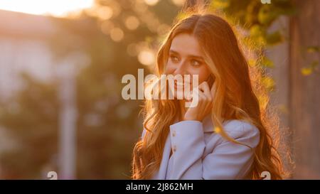 Portrait de la belle femme d'affaires jeune femme caucasienne jeune fille millénaire modèle femelle se tient à l'extérieur dans la ville lever de soleil fond du soleil coucher du soleil Banque D'Images