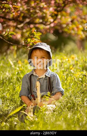 Enfant élégamment habillé, garçon avec chien d'animal, jouant dans le parc sur la flûte, appréciant sa compagnie d'ami d'animal de compagnie Banque D'Images