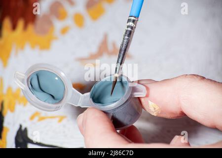 Pot à peinture acrylique avec pinceau pour la peinture par numéros gros plan. Main femelle avec brosse. Loisirs à la maison, loisirs créatifs. Peintures numérotées. Peinture par Banque D'Images