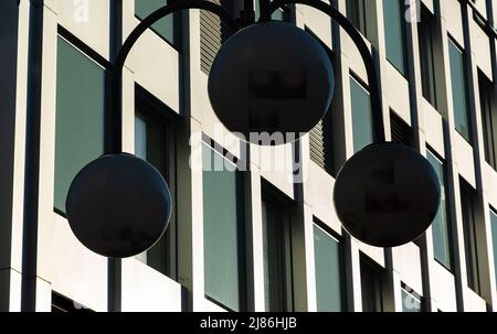 Silhouette d'une lampe de rue ronde moderne et façade d'un bâtiment moderne, photographiée contre le soleil Banque D'Images