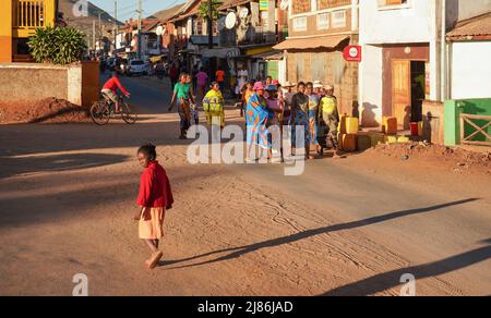 Ihosy, Madagascar - 05 mai 2019: Groupe de femmes et d'hommes malgaches inconnus en vêtements lumineux marchant dans la rue de la ville, le soleil de l'après-midi leur brille, un Banque D'Images