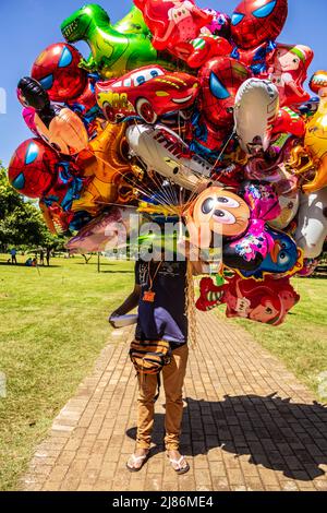 Goias, Brésil – 21 avril 2022 : le vendeur de ballons dans un parc. Une personne tenant plusieurs ballons qui cachent son visage. Banque D'Images