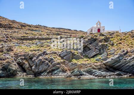 Petite église grecque sur la colline rocheuse, sur l'eau de mer turqoise, fond bleu ciel, jour ensoleillé d'été. Chapelle Agios Ioannis, île de Kythnos, Grèce Banque D'Images