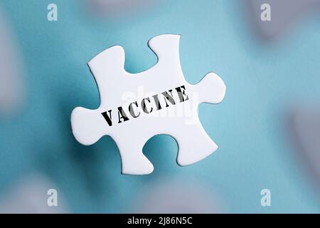 Mot de vaccin sur des pièces de puzzle isolées sur fond bleu flou. Concept de pandémie et d'éclosion. Banque D'Images