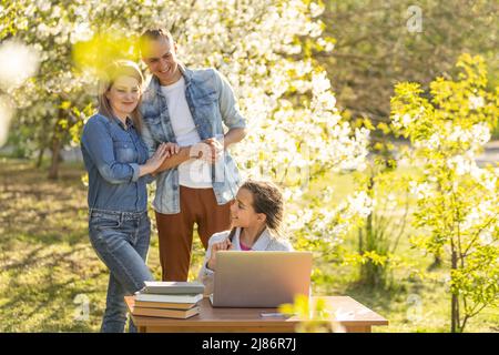 Jeune caucasien souriant famille avec petite fille regarder l'écran d'ordinateur portable regarder la vidéo drôle en ligne. Bonne maman et papa s'amusent à utiliser l'ordinateur avec Banque D'Images