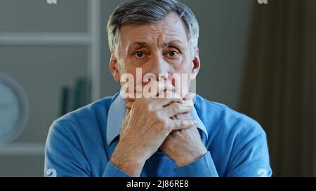 Déprimé désespéré vieux caucasien homme choqué triste âgé mature 60s homme se sentant inquiet regardant la caméra couvercle bouche tenant la tête stressée Banque D'Images