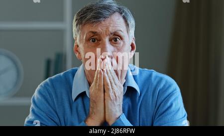 Déprimé frustré vieux caucasien homme choqué triste âgé mature 60s homme se sentant inquiet regardant la caméra couvercle bouche tenant la tête stressée Banque D'Images