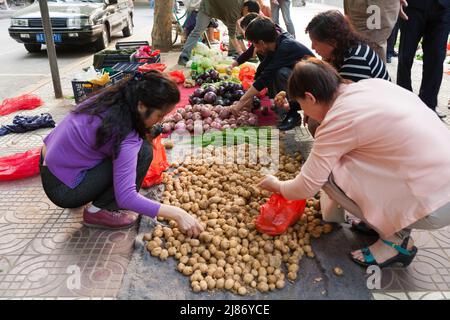 Le marché du trottoir stalle avec des fruits et des légumes disposés sur le sol et les clients à la recherche de produits à acheter. Ville de Xi'an en Chine RPC. (125) Banque D'Images