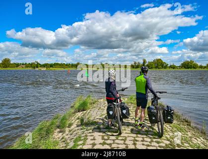 12 mai 2022, Brandebourg, Genschmar: Deux cyclistes se tiennent sur une groyne sur la frontière germano-polonaise Oder. Fin avril, la Commission européenne de Bruxelles a annoncé que le paysage culturel Oderbruch de Brandebourg avait reçu le label européen du patrimoine. Le plus grand paysage politique peuplé d'Europe a été honoré parce que les idéaux et l'histoire de l'UE sont symbolisés ici d'une manière spéciale. La région a été créée après le drainage il y a près de 270 ans, a été installée avec des colons par le roi prussien Frederick II et est préservée comme un habitat avec un système ingénieux d'eau. Photo: Patri Banque D'Images